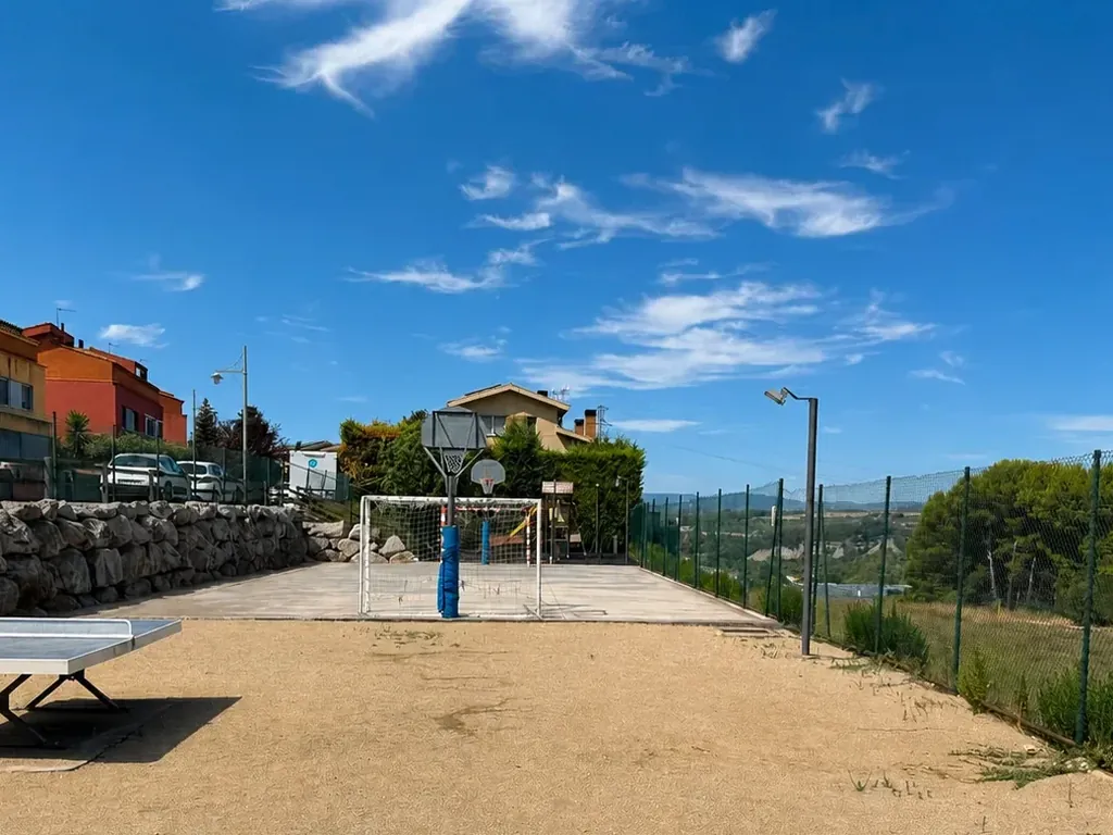 La pista polideportiva y la zona de juego, con el valle al fondo